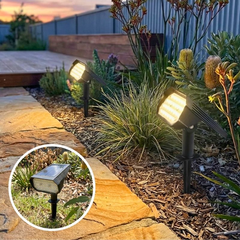 Solar-powered outdoor lights illuminating a garden pathway with plants and wooden deck in the background.